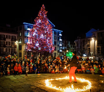 Cracheur de feu au pied d'un sapin de Noël illuminé