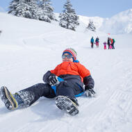 Enfant dévalant une pente enneigée en luge