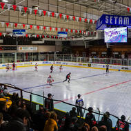 Match de hockey sur glace vu depuis les gradins d'une patinoire olympique